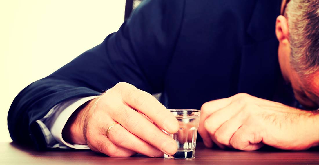 un hombre con un vaso de vodka durmiendo en la mesa