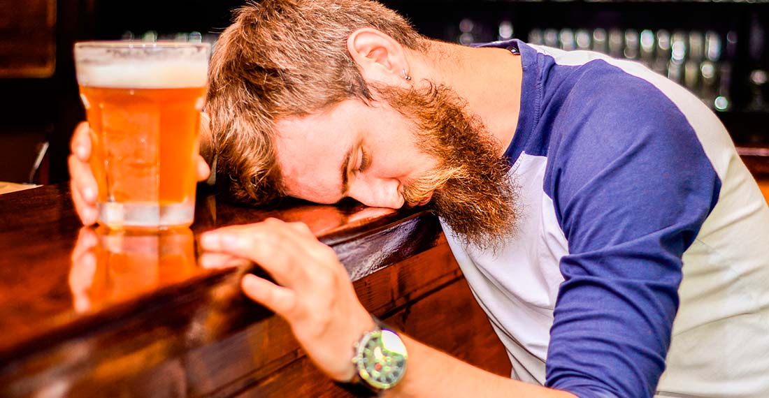 un hombre con una jarra de cerveza durmiendo detrás de la barra